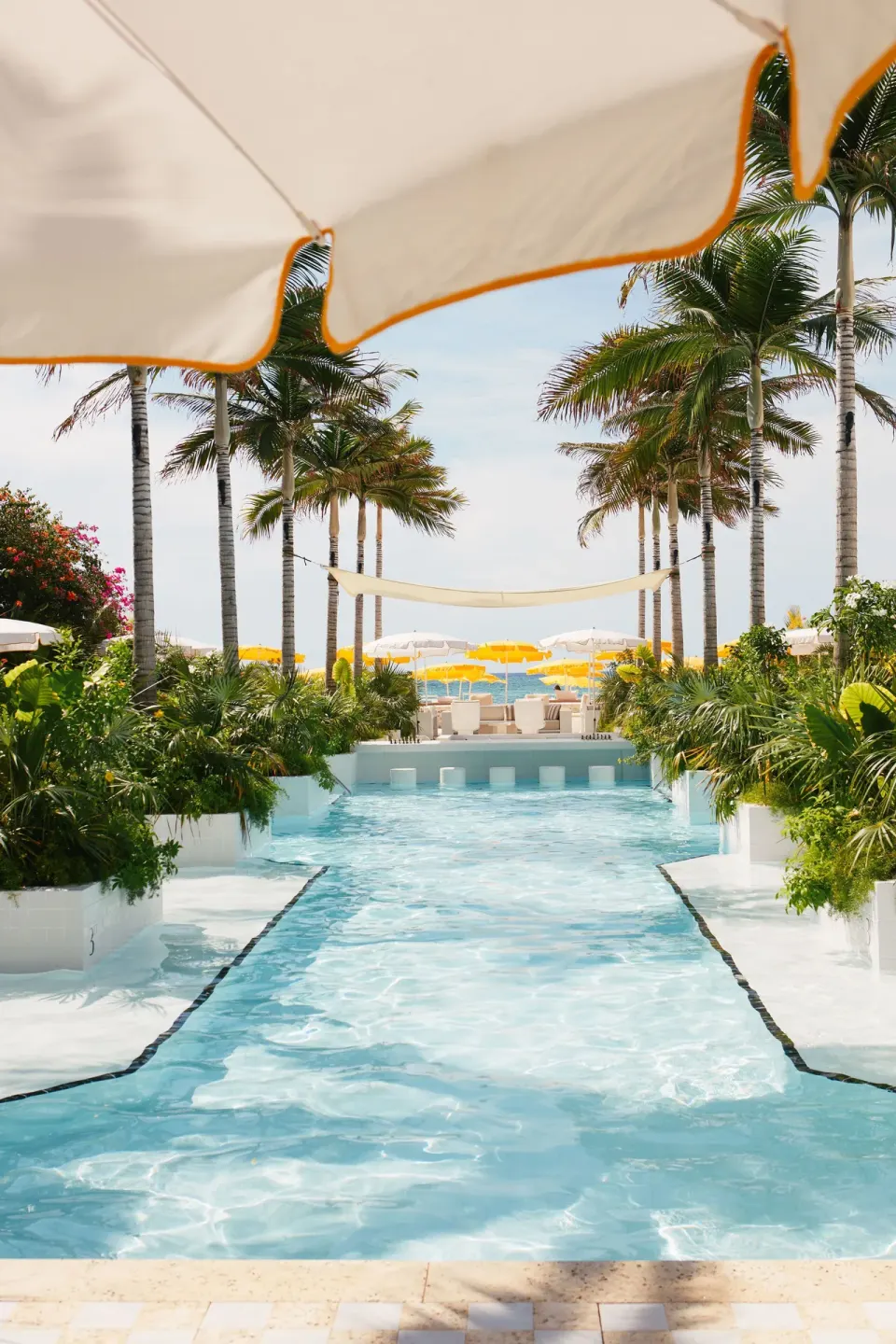 Long reflecting pool framed by palm trees leading to the beach at Palm Heights.