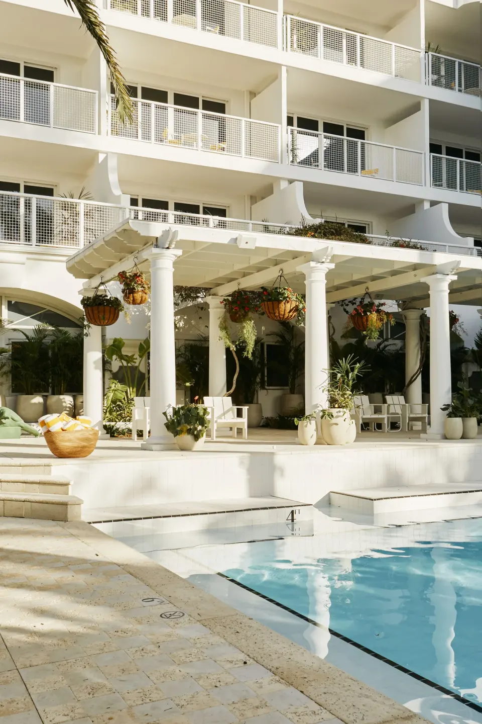 Pool edge with pergola seating, hanging plants and hotel balconies at Palm Heights.