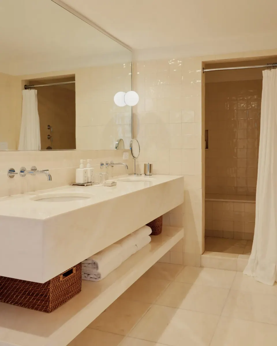 Stone-style rectangular sink with open shelving and shower entrance at Palm Heights.