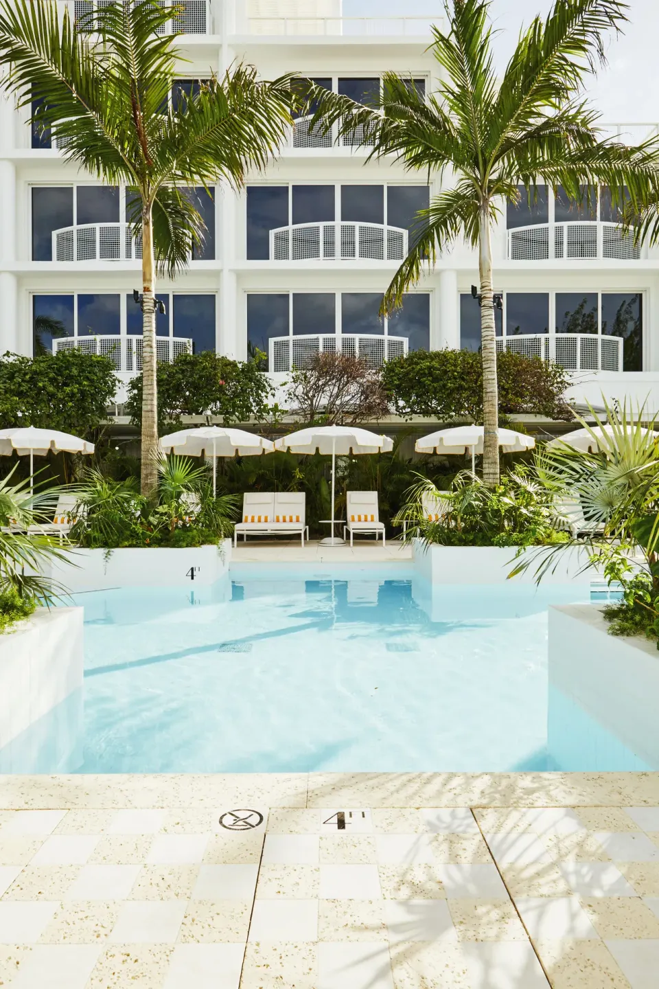 Small resort pool with palm trees and hotel facade at Palm Heights.