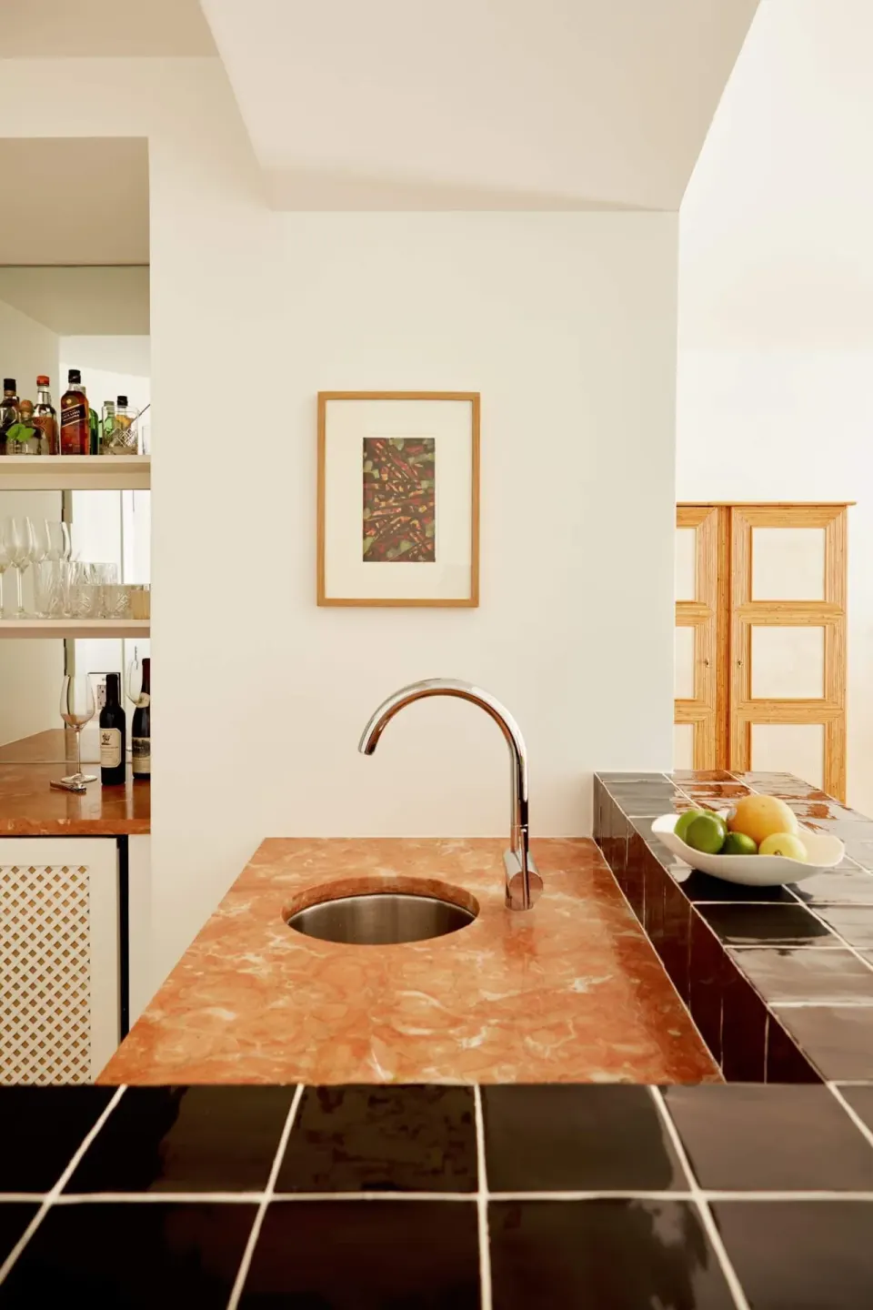 Stone and black-tile counter with sink and fruit bowl in a Palm Heights suite