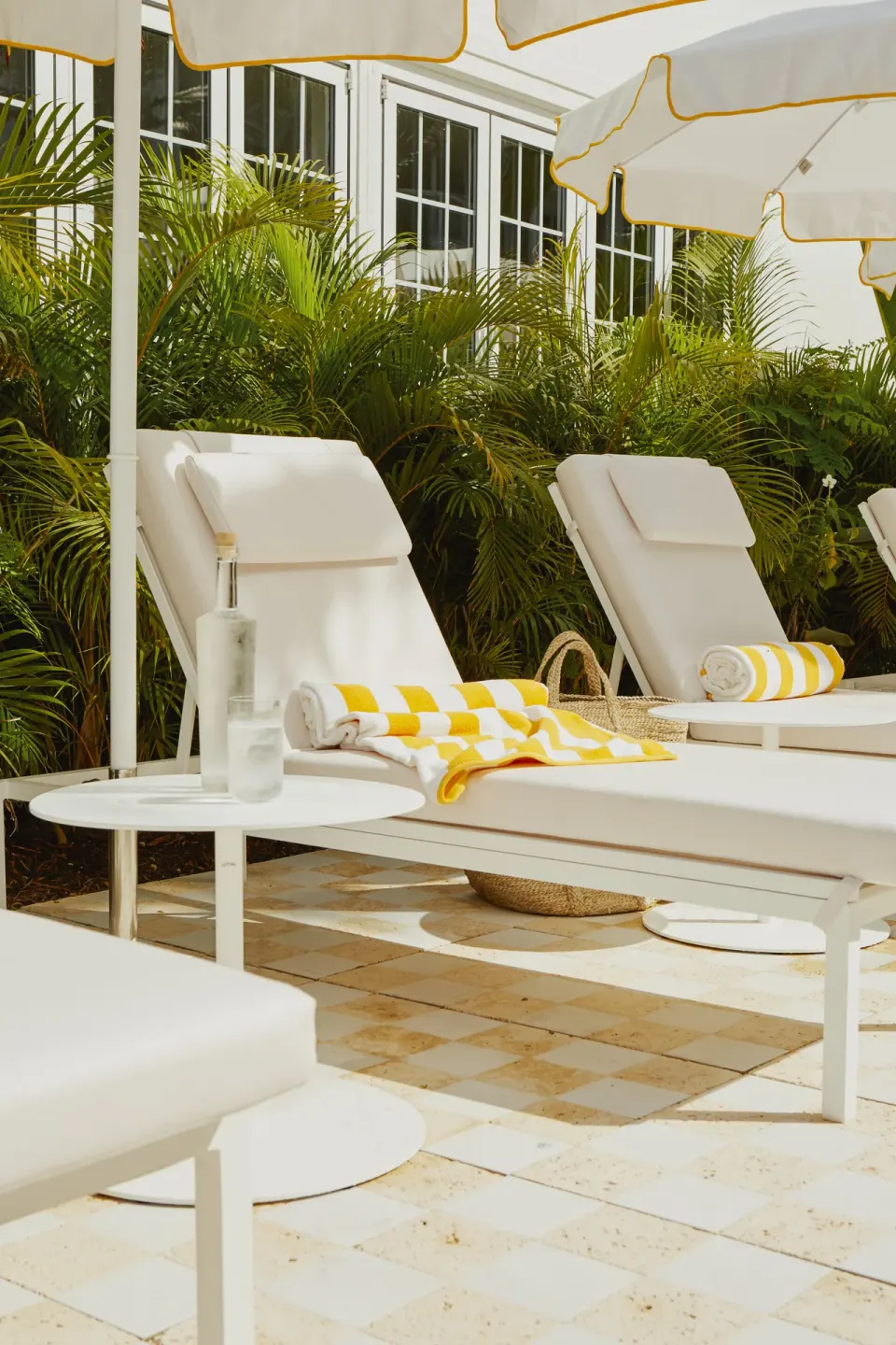Close-up of a padded sun lounger with a striped towel and water bottle at Palm Heights.