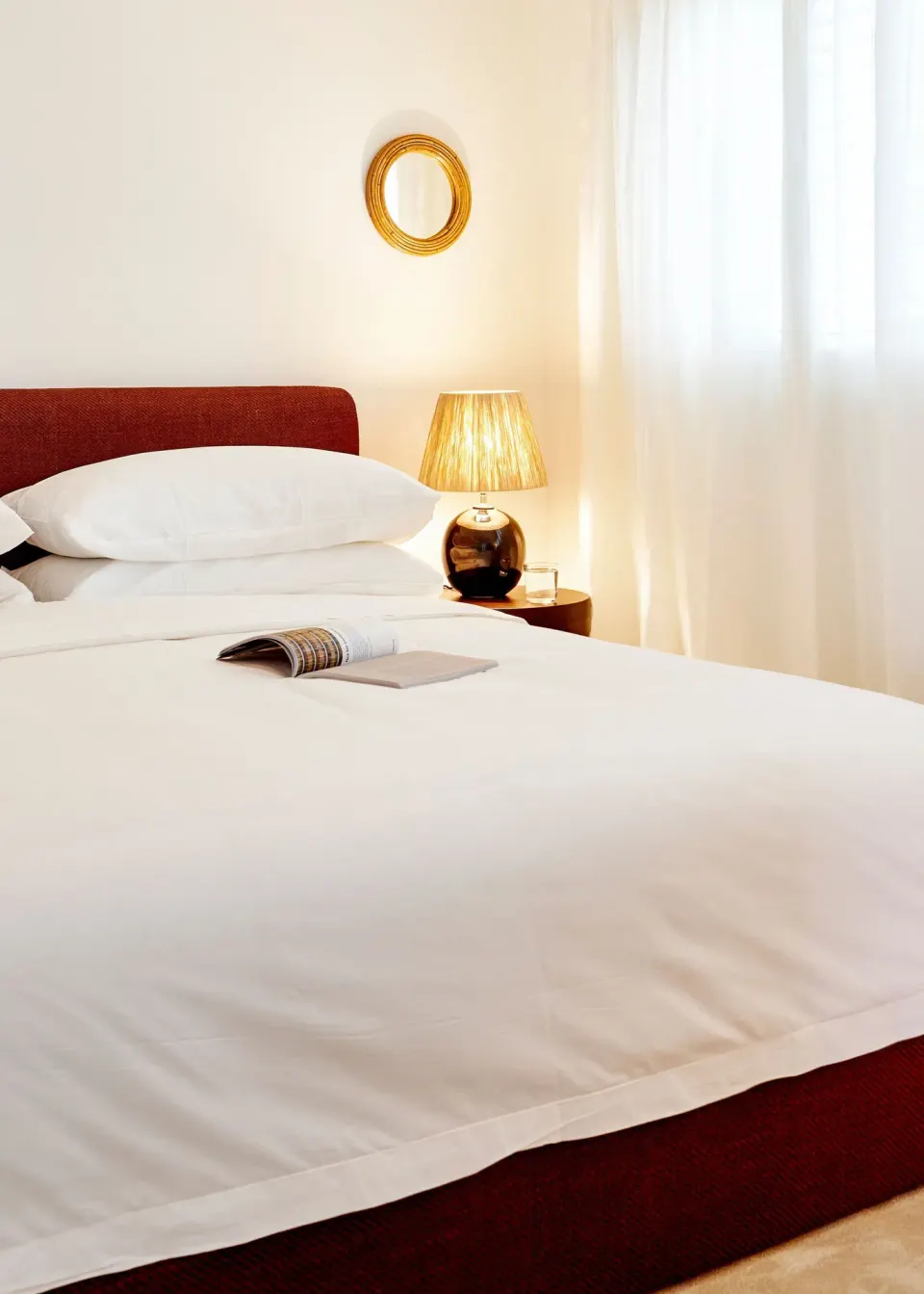 Front view of a bed with a red upholstered base and bedside lamp at Palm Heights.