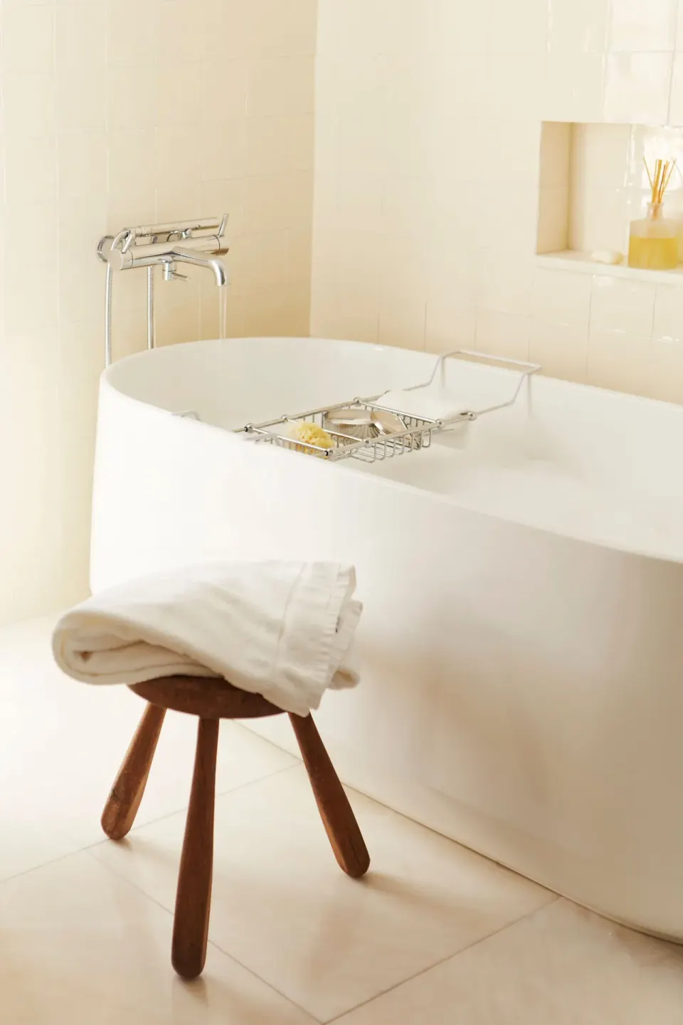 Freestanding tub with bath caddy and folded towel on a wooden stool at Palm Heights.