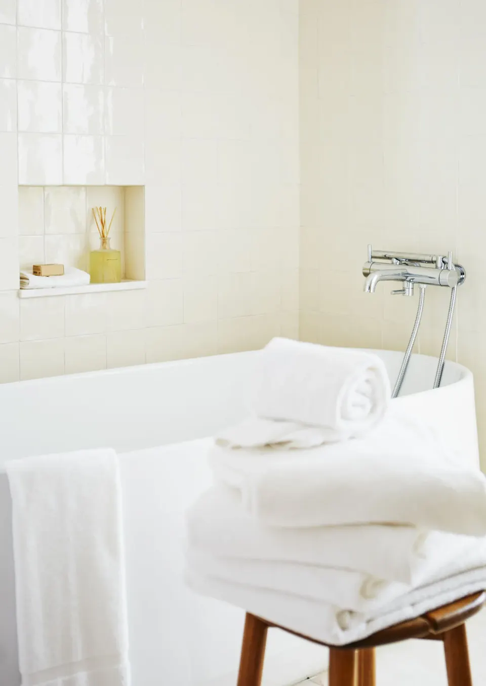 Freestanding bathtub with rolled towels and recessed shelf in Palm Heights bathroom.