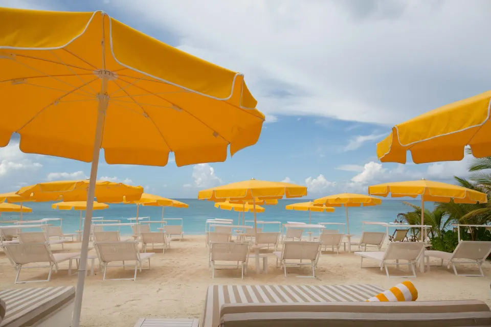 Rows of yellow beach umbrellas and loungers on the sand at Palm Heights.