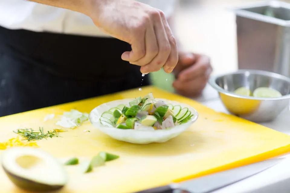 Chef finishing a plated cucumber salad at Palm Heights