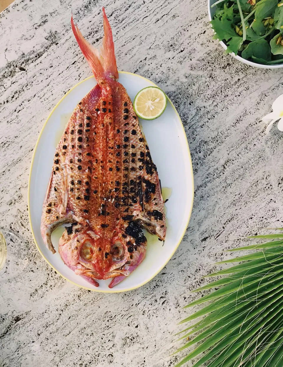 Whole grilled fish on a platter with lime at Palm Heights