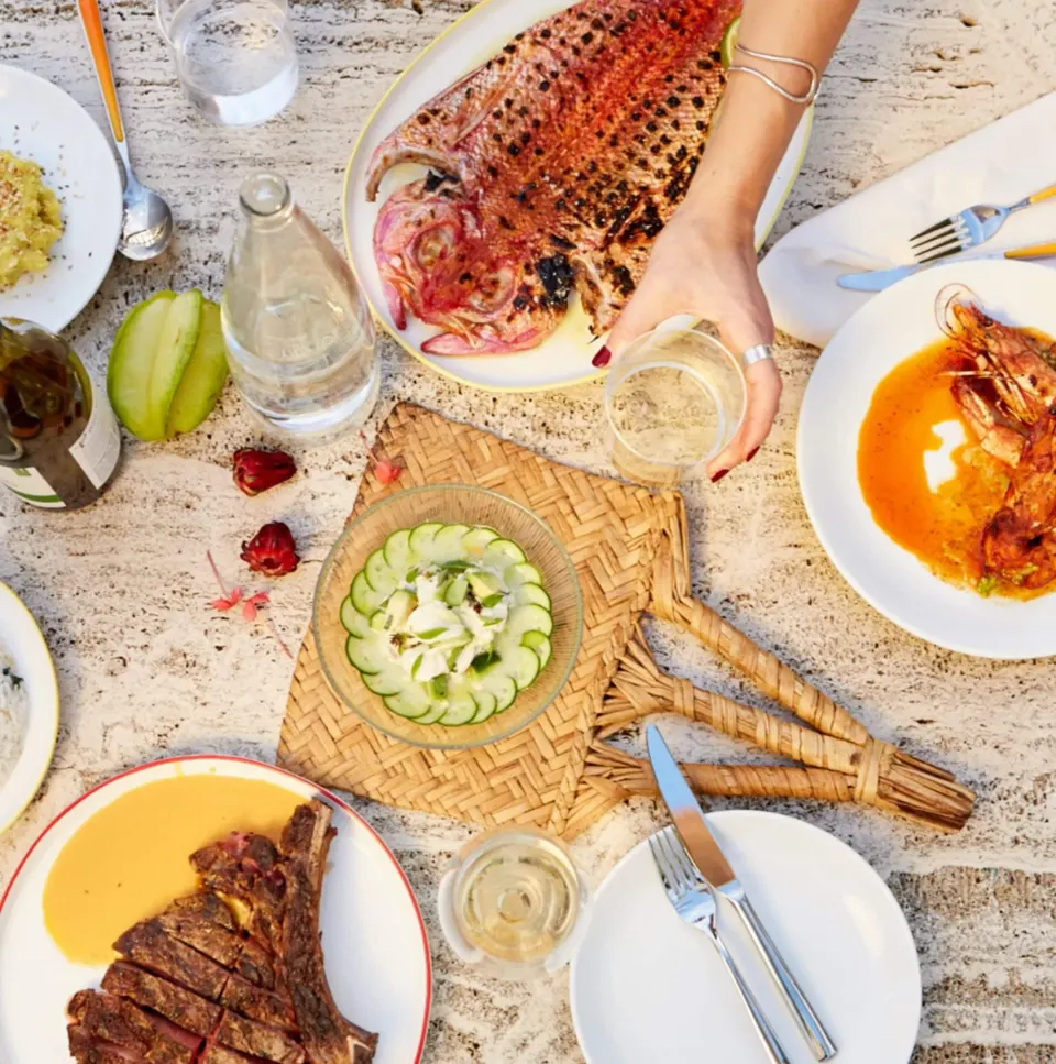 Overhead table of assorted dishes and a hand holding a glass at Palm Heights