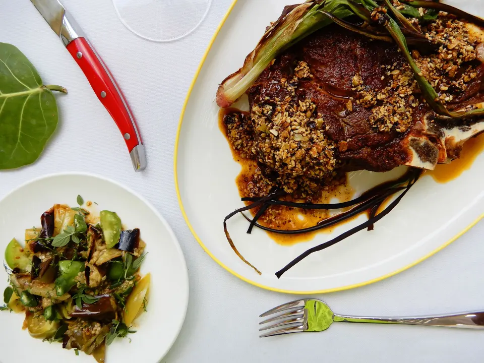 Plated steak and vegetable dish on white tabletop at Palm Heights dining