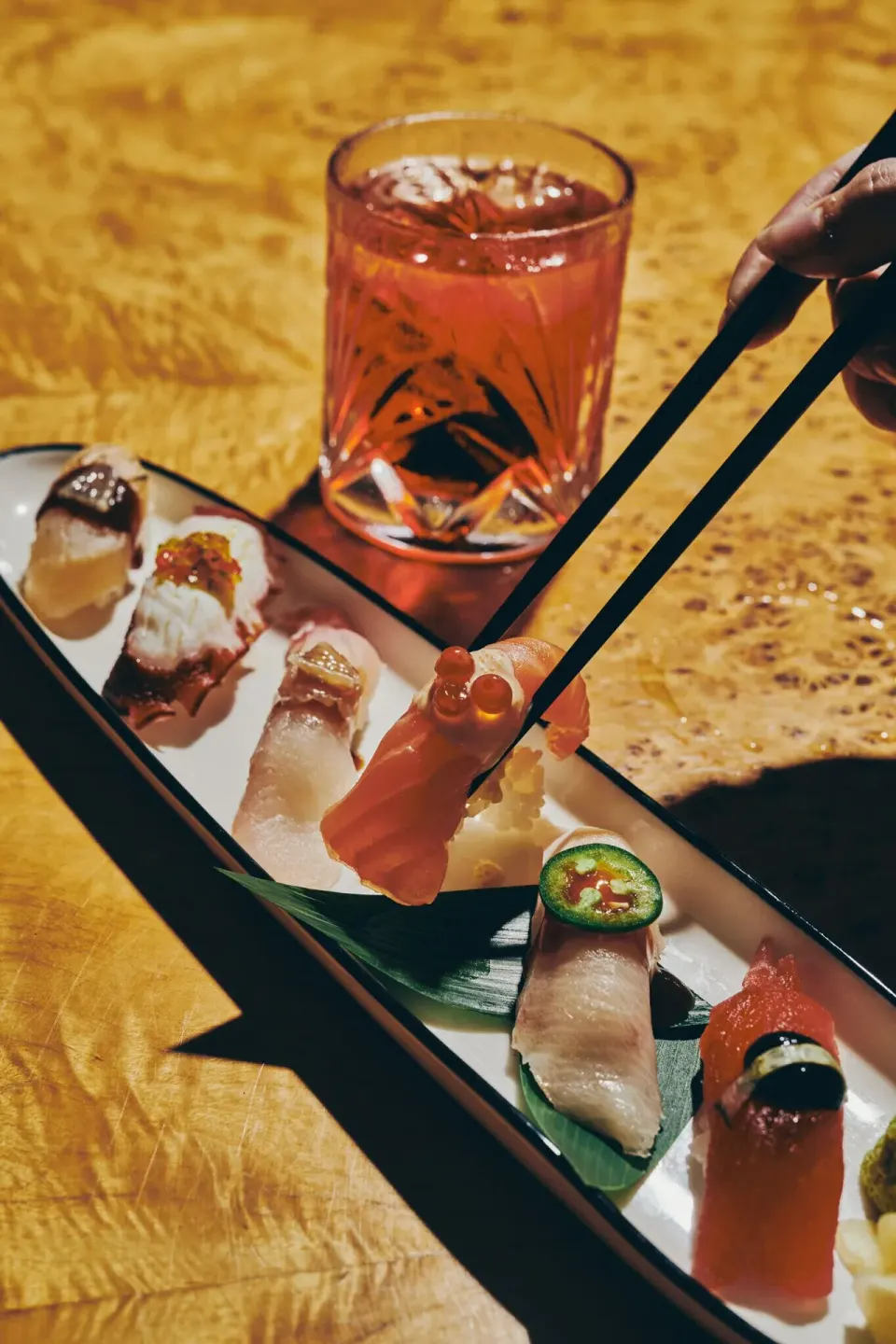 Assorted nigiri sushi with chopsticks and a cocktail at Palm Heights