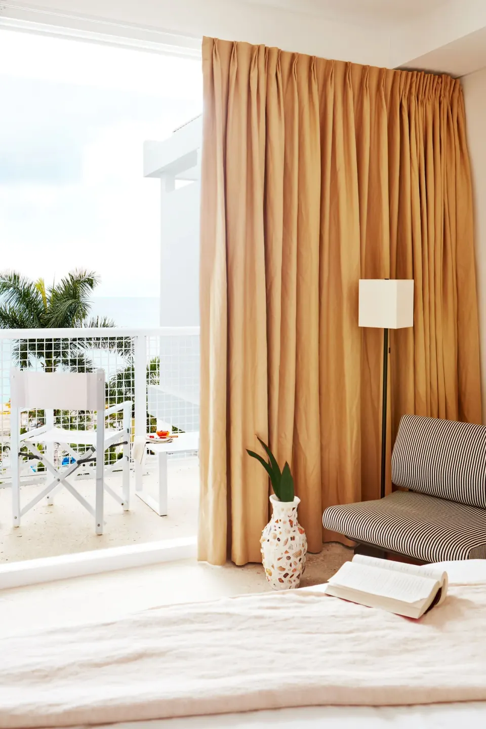 Seating area and balcony view with curtains in a Deluxe Multiple Beds Ocean View Suite at Palm Heights
