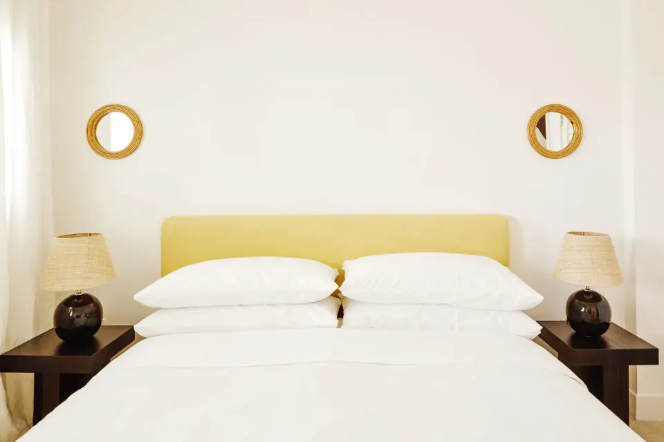 Neatly made bed with stacked pillows in a Deluxe Multiple Beds Ocean View Suite at Palm Heights
