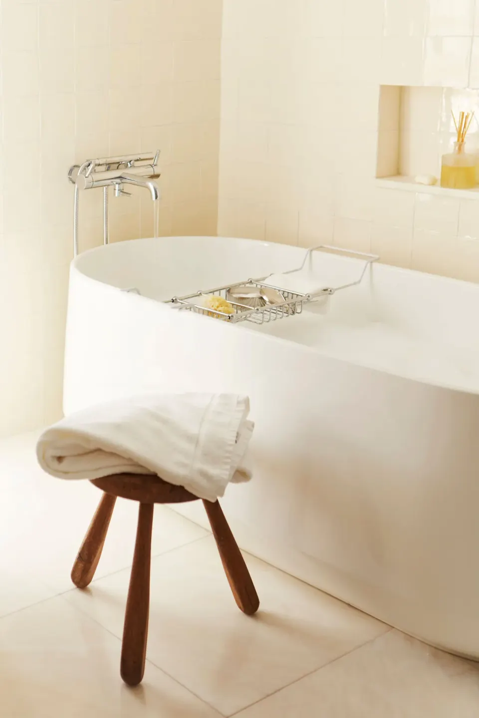 Freestanding white bathtub with stool and towel in a Deluxe Suite bathroom at Palm Heights.
