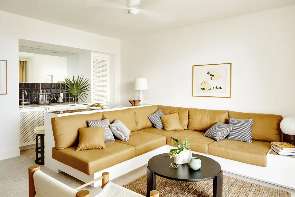 Corner living room with large tan sectional sofa in a Deluxe Suite at Palm Heights.