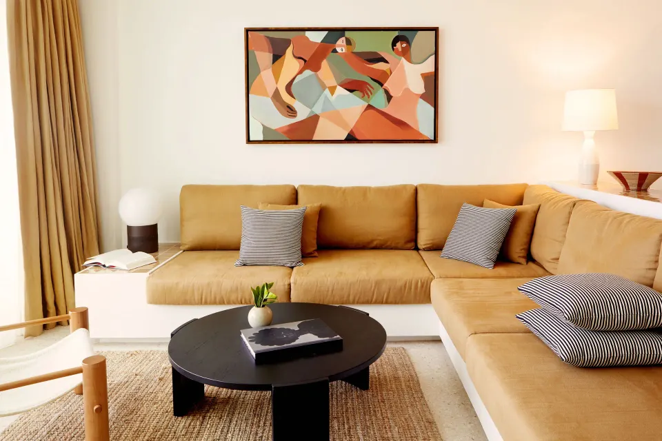 Seating area with tan sectional and artwork in a Deluxe Suite at Palm Heights.