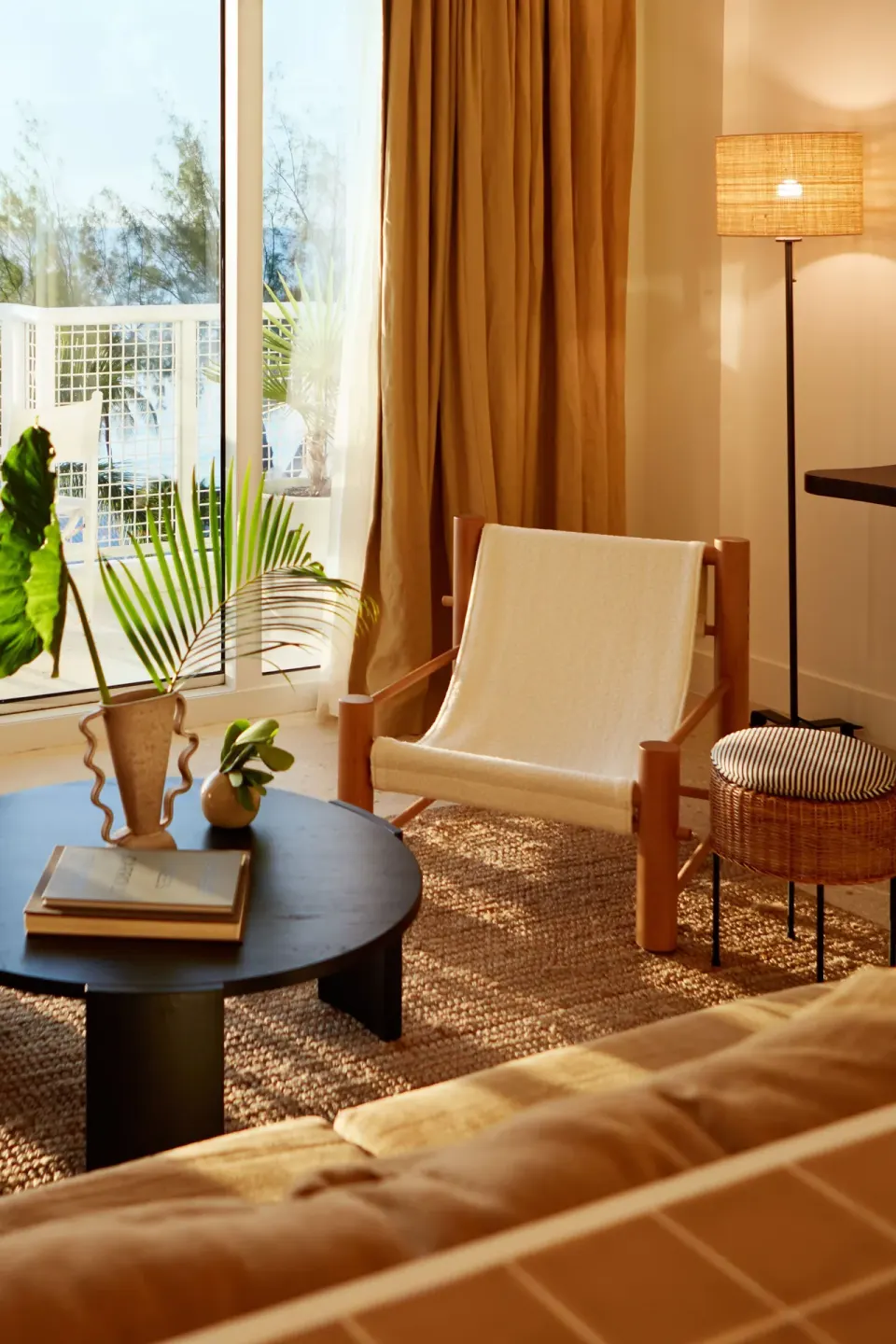 Sunlit seating area with armchair and floor lamp in a Deluxe Suite at Palm Heights.