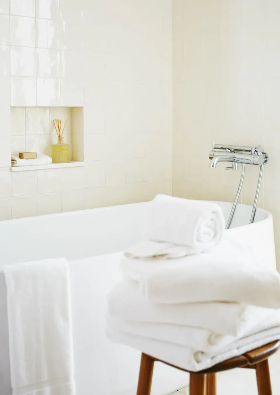 Rolled towels stacked on a stool beside a bathtub in a Deluxe Suite bathroom at Palm Heights.