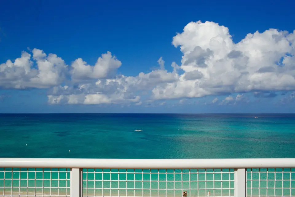 Clear turquoise ocean and sky seen over the suite balcony railing at Palm Heights