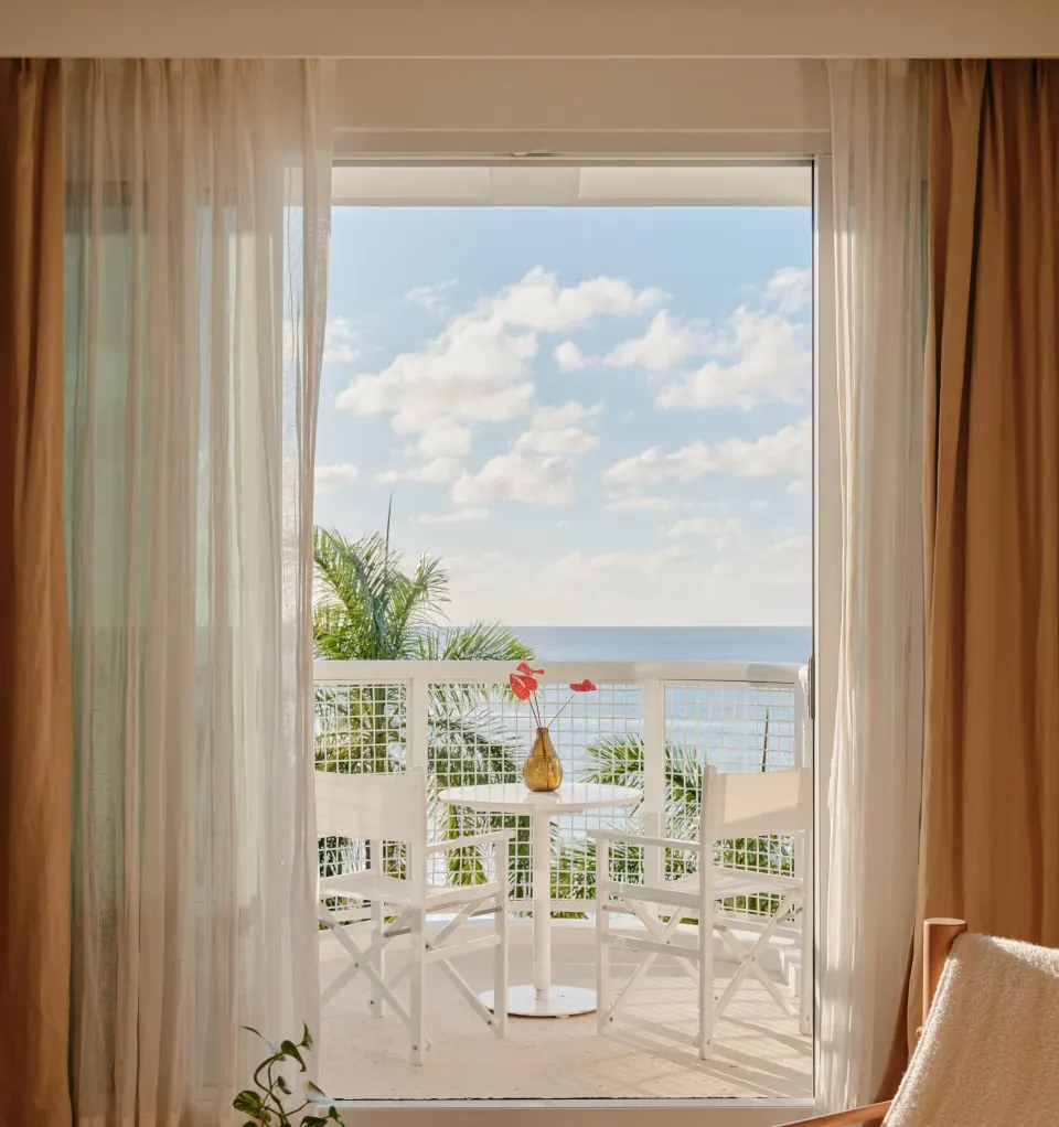 Balcony table and chairs with ocean view from an Ocean Facing Penthouse at Palm Heights.