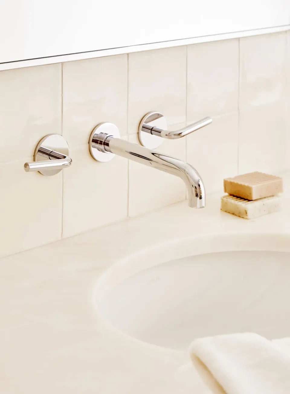 Close-up of chrome wall-mounted faucet and sink in a Palm Heights penthouse bathroom.