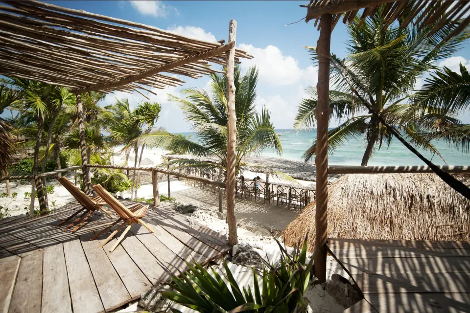 Wooden deck with loungers overlooking the beach and ocean at Papaya Playa Project