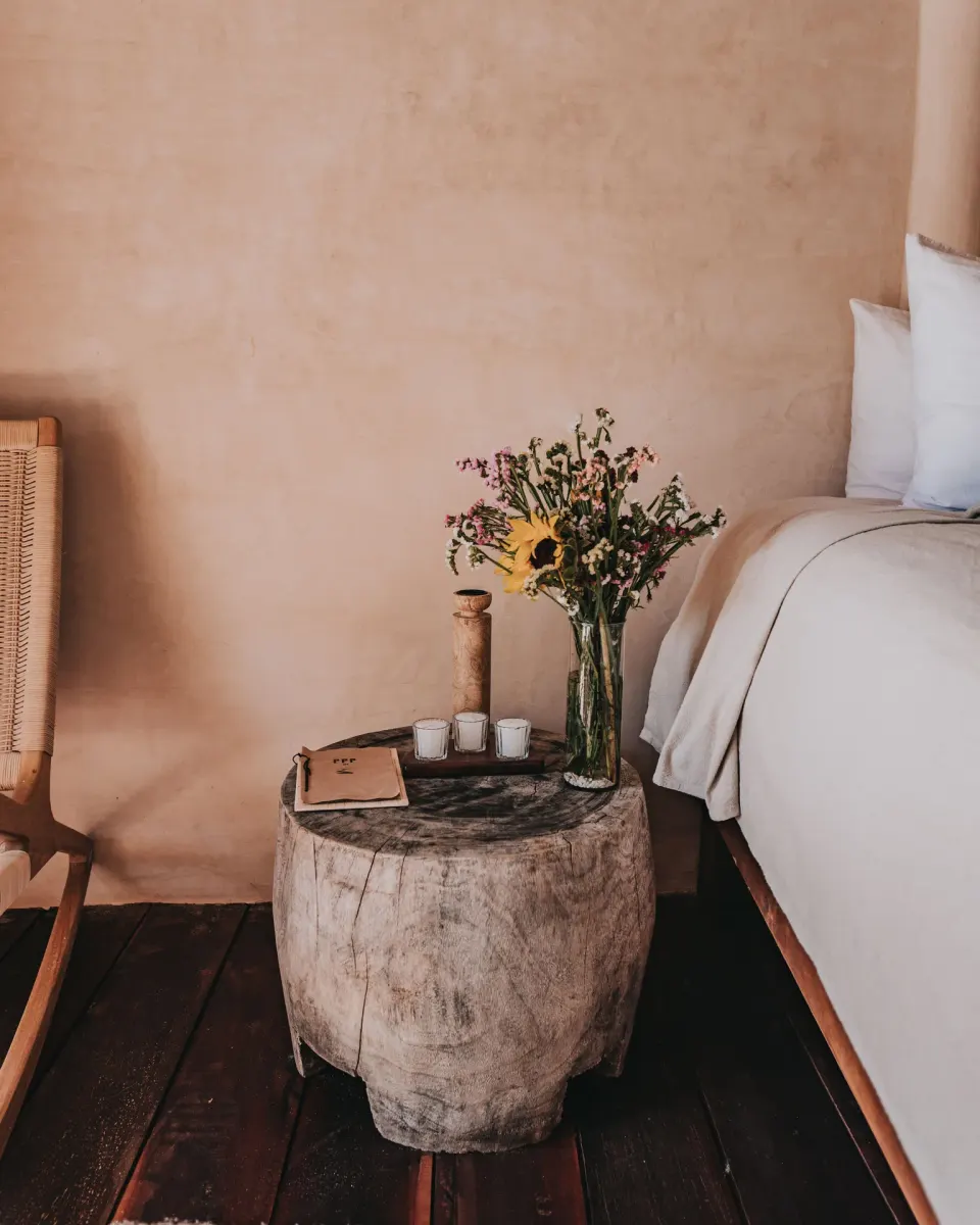 Bedside stump table with flowers next to a king bed at Papaya Playa Project