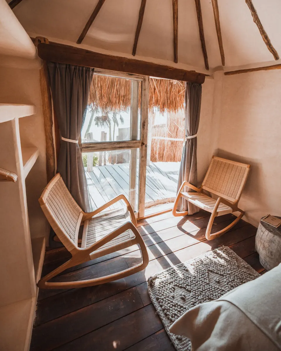 Two woven rocking chairs by a glass door in a guest bungalow at Papaya Playa Project
