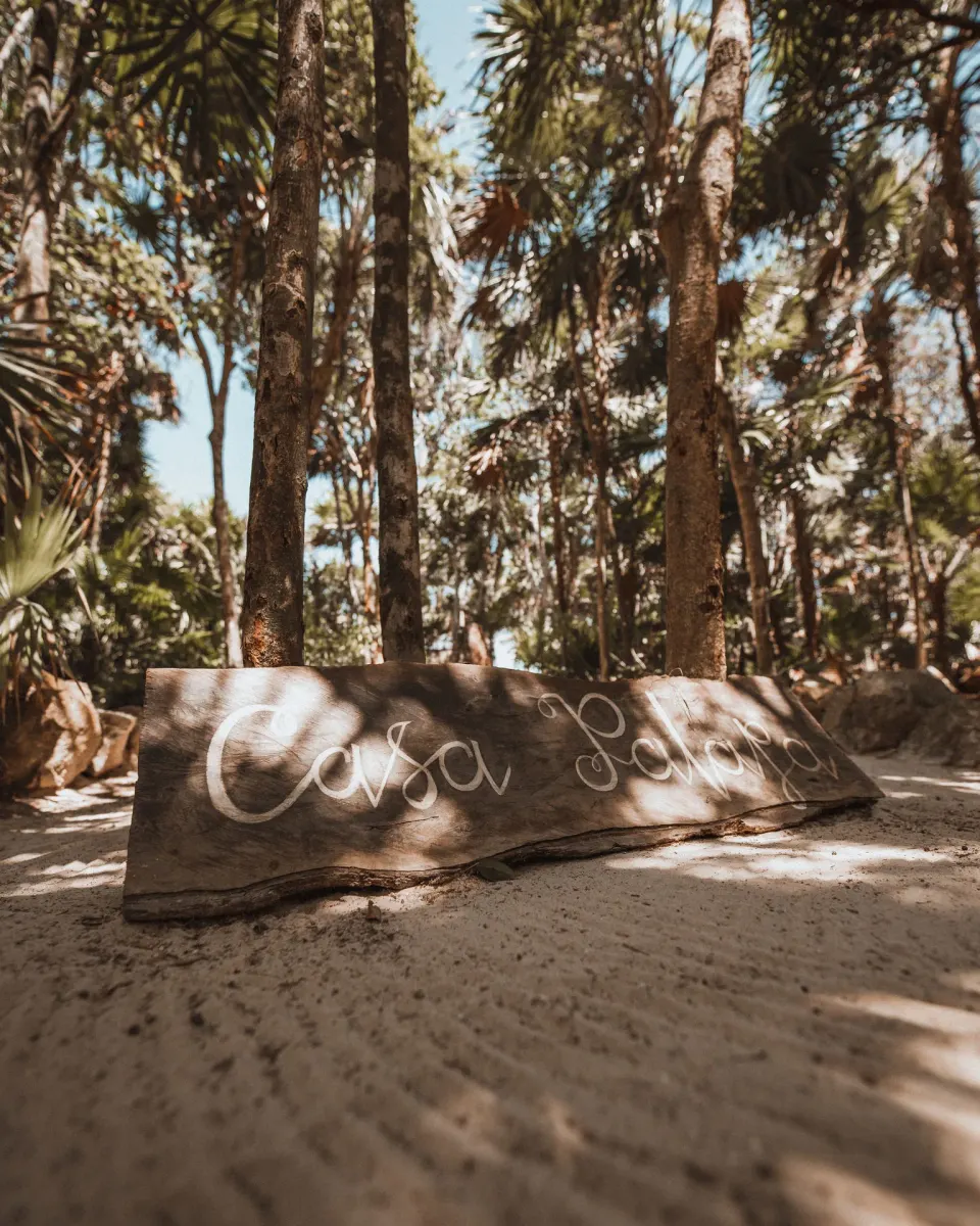 Wooden 'Casa Palapa' sign on the sandy grounds at Papaya Playa Project.