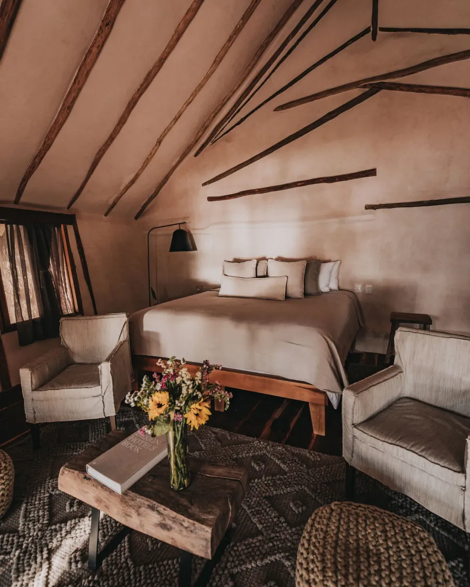 Cozy guest room with king bed and rustic beams at Papaya Playa Project.