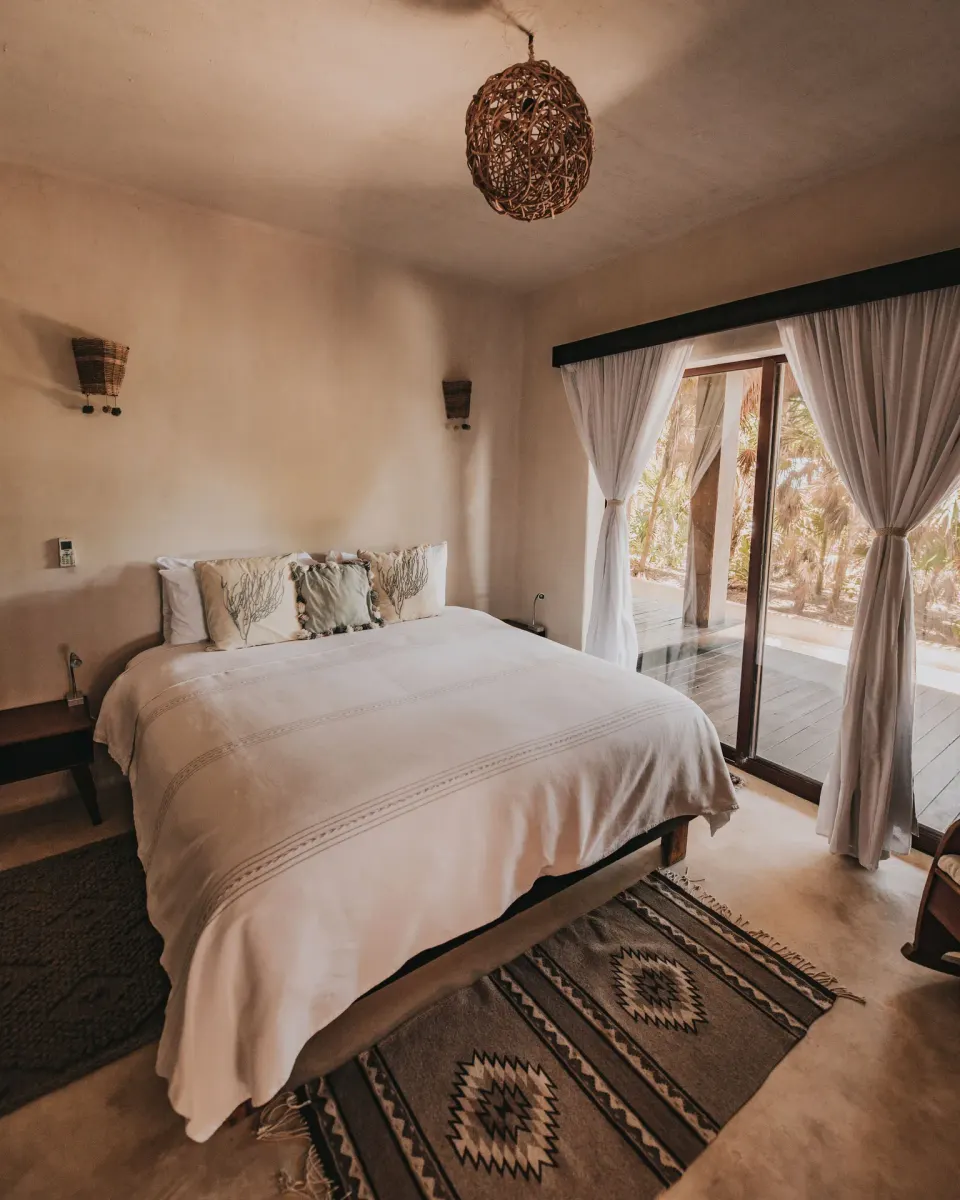 Bright guest room with king bed and sliding glass doors at Papaya Playa Project.