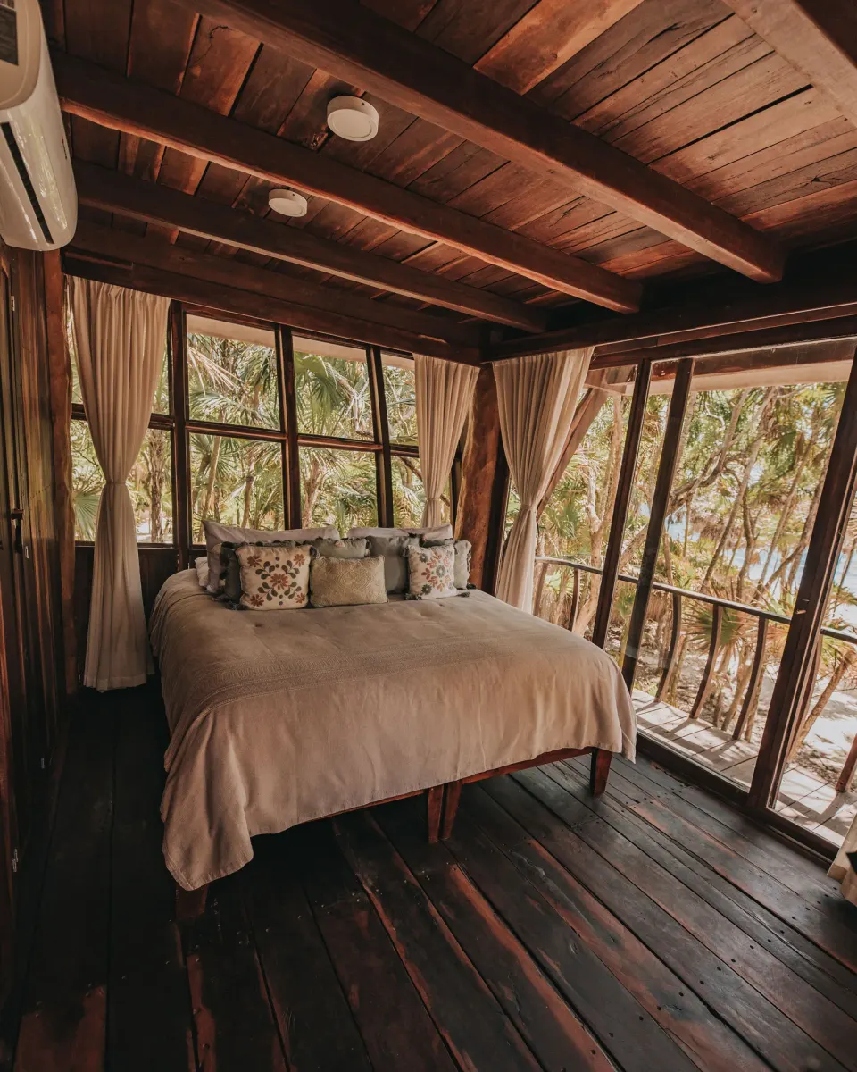 Wooden loft bedroom with floor-to-ceiling windows at Papaya Playa Project.