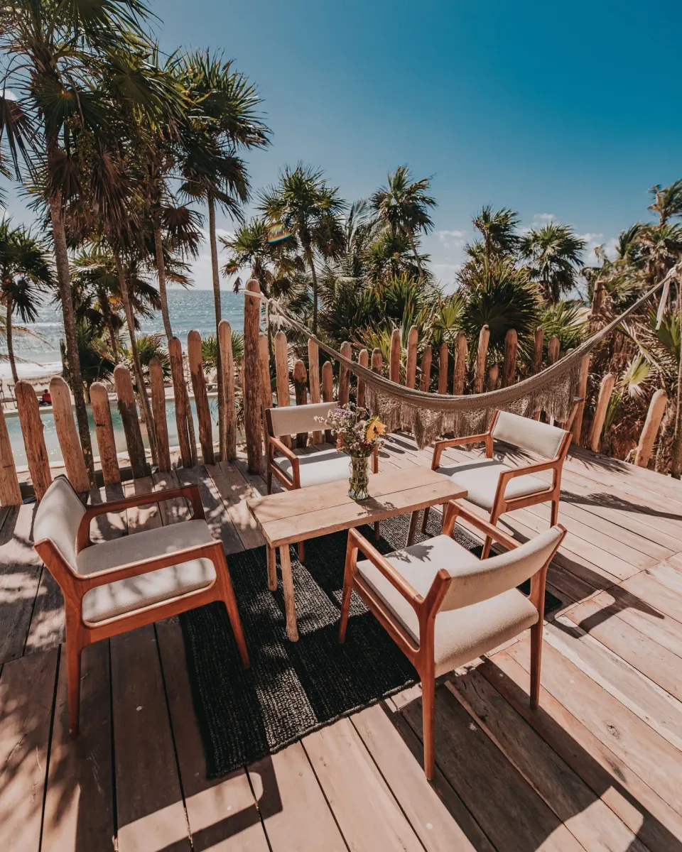 Ocean-view wooden deck with chairs and a hammock at Papaya Playa Project