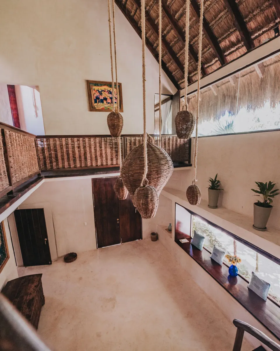 Open two-level lobby with hanging wicker pendants at Papaya Playa Project.