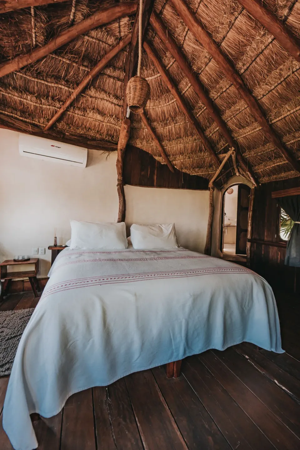 Thatched-roof bedroom with a king bed and tropical decor at Papaya Playa Project