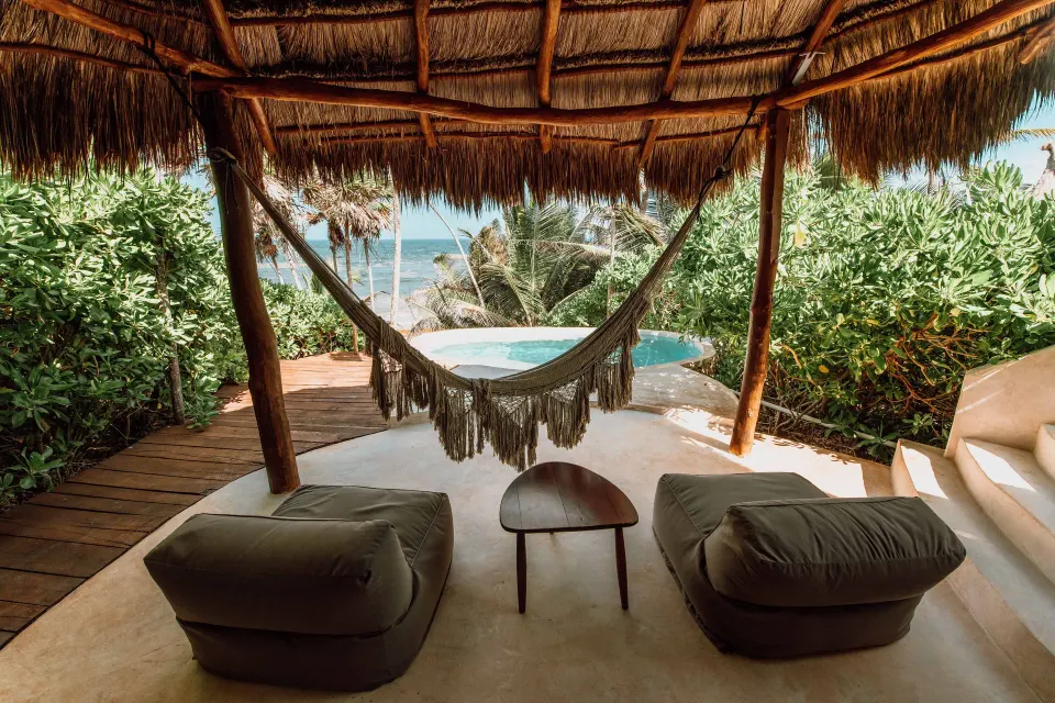 Shaded palapa seating with a hammock and private plunge pool overlooking the sea at Papaya Playa Project
