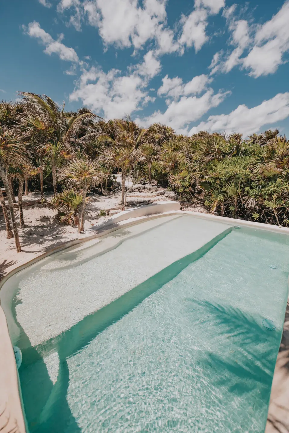 Shallow turquoise pool with palm trees at Papaya Playa Project.