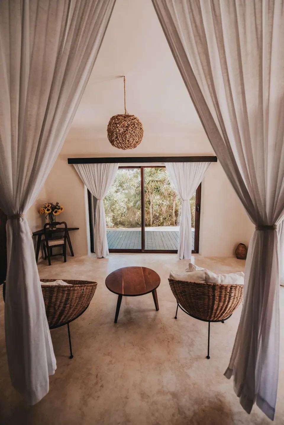 Curtained sitting area with two wicker chairs facing a sliding door at Papaya Playa Project.