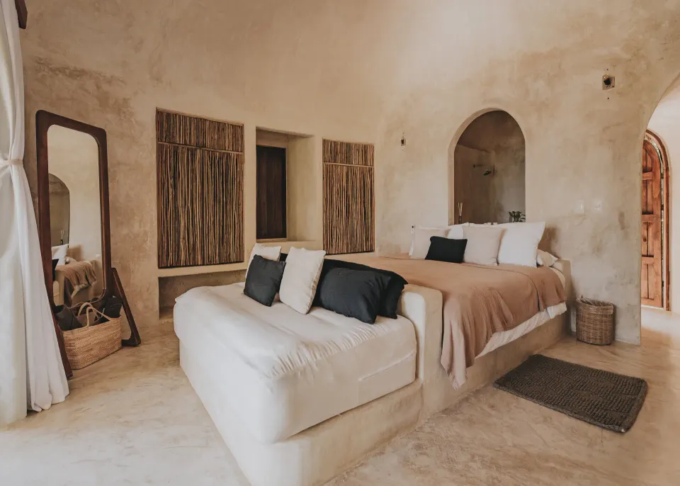 Neutral-toned stucco suite with a king bed and built-in sofa at Papaya Playa Project.