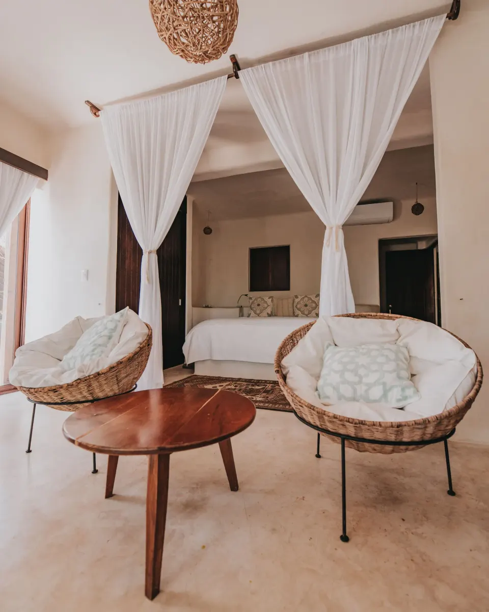 Seating area and canopy bed inside a guest room at Papaya Playa Project