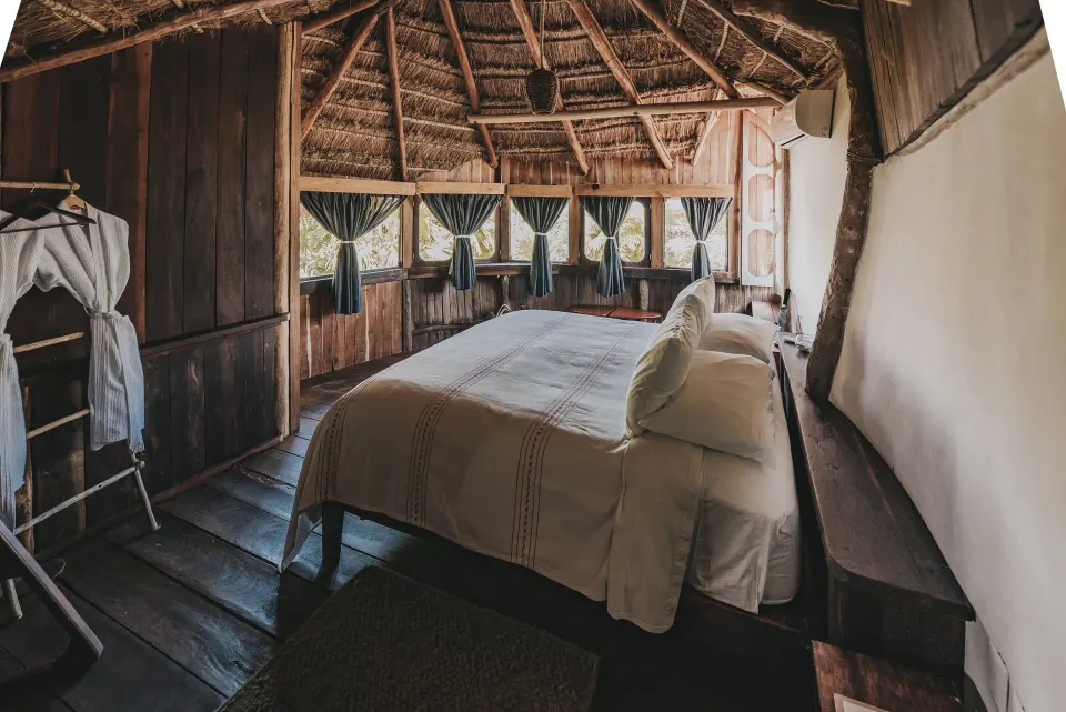 Rustic bedroom with king bed and curved thatch ceiling at Papaya Playa Project