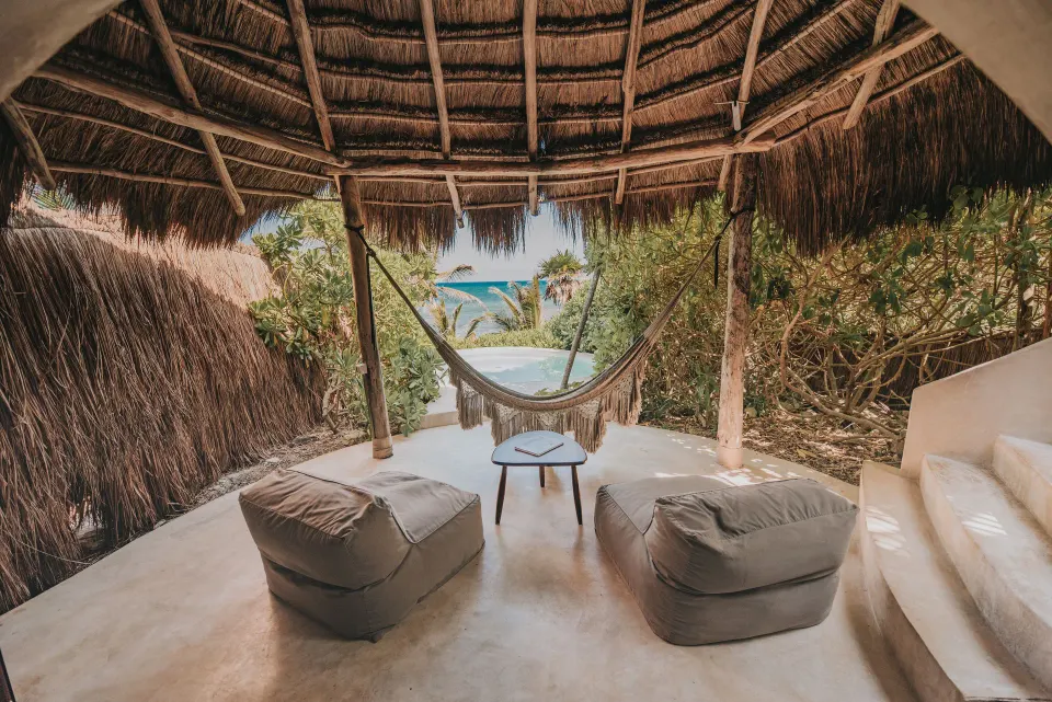 Thatched cabana with hammock and seating facing the sea at Papaya Playa Project.