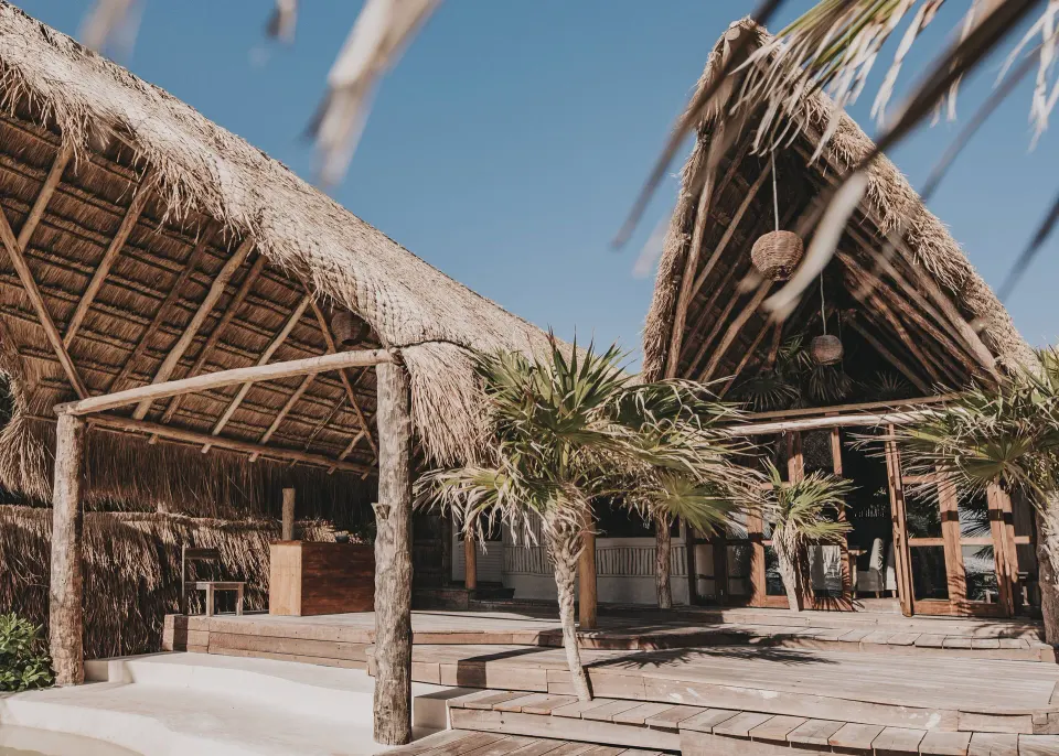 Low timber pavilions and wooden deck at the resort entrance at Papaya Playa Project