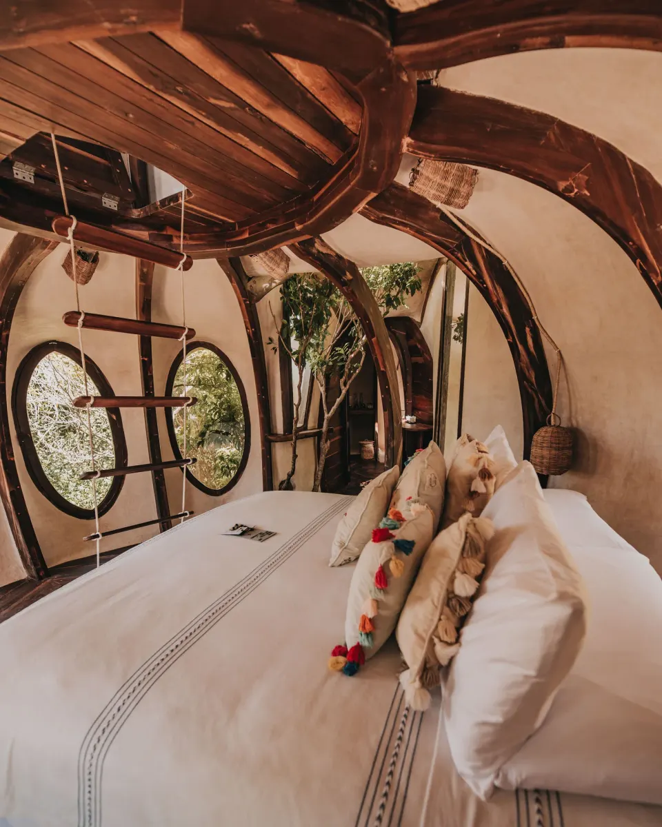 Close-up of king bed with decorative pillows in a treehouse room at Papaya Playa Project