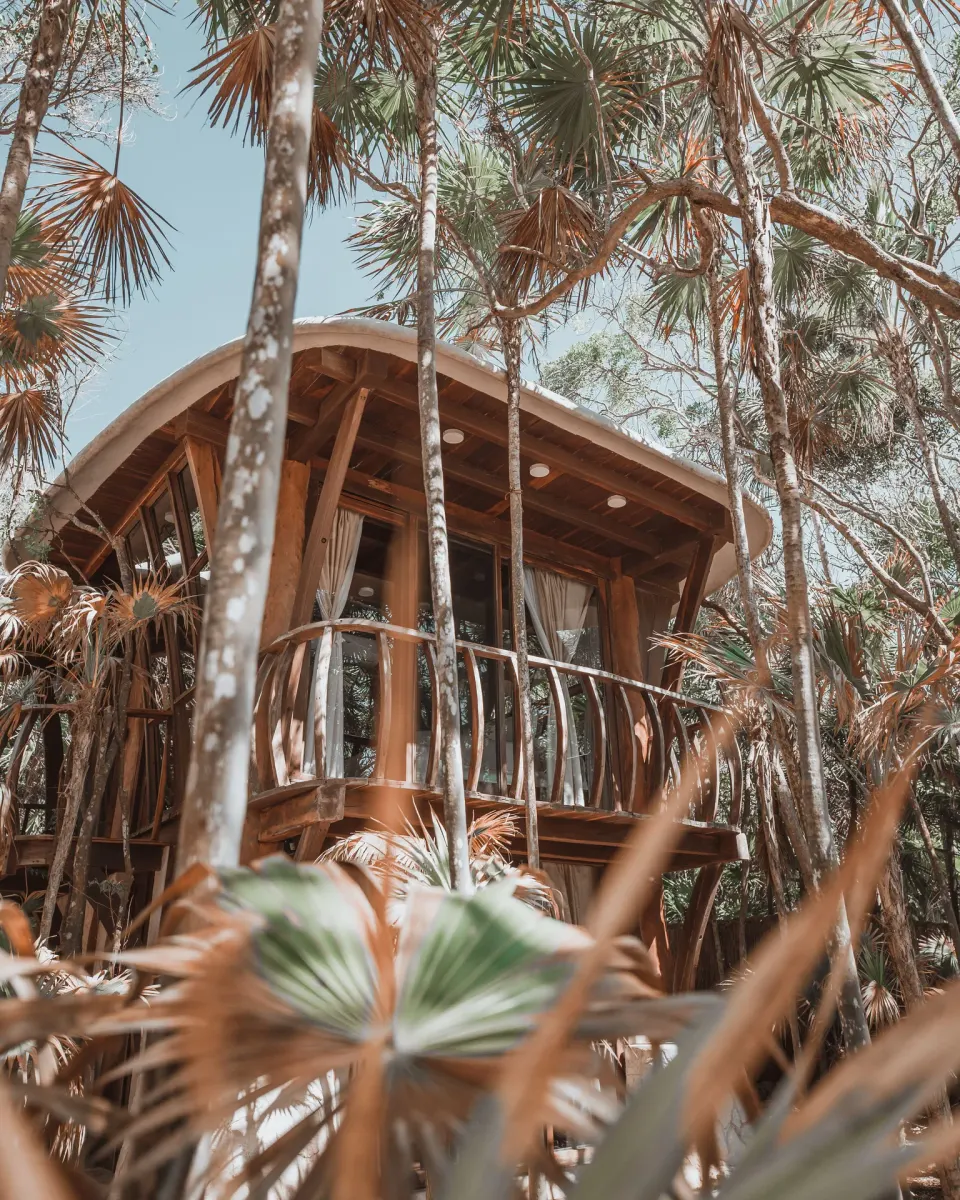 Wooden round-treehouse bedroom with a king bed and ladder at Papaya Playa Project