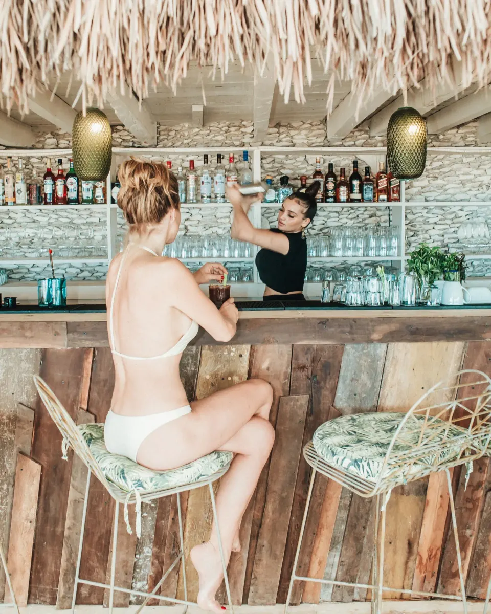 Barkeeper mixing a cocktail for a woman at the bar at Papaya Playa Project
