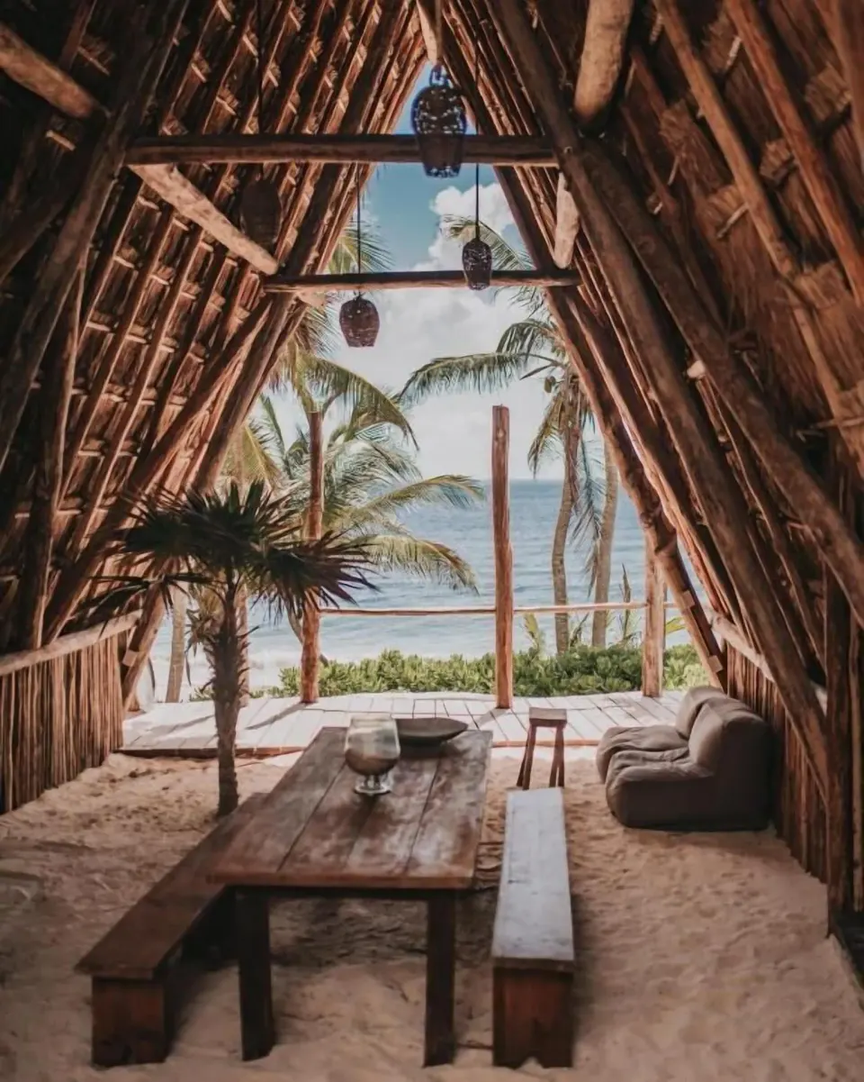 Beachfront palapa dining area with rustic table and ocean view at Papaya Playa Project