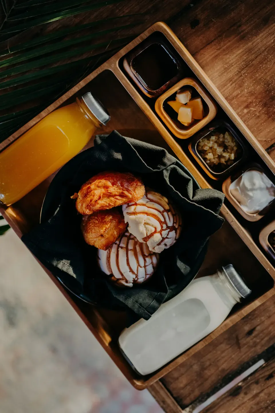 Close-up breakfast tray with pastries, condiments and bottled drinks at Papaya Playa Project