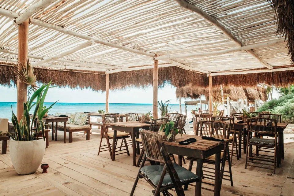 Open-air dining deck with wooden tables and ocean views at Papaya Playa Project