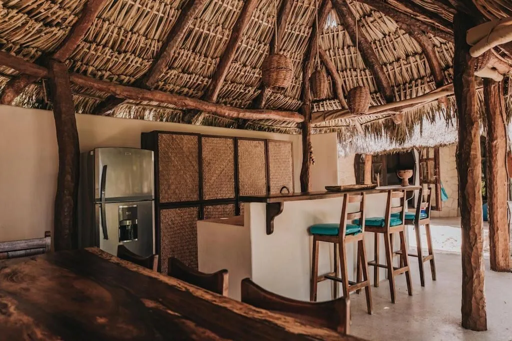 Thatched bar with high stools and woven panels at Papaya Playa Project
